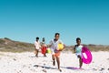 African american playful children running and parents walking on sandy beach under clear blue sky Royalty Free Stock Photo