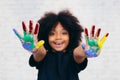 African American playful and creative kid getting hands dirty with many colors