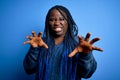 African american plus size woman with braids wearing casual sweater over blue background smiling funny doing claw gesture as cat, Royalty Free Stock Photo