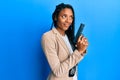 African american police woman holding gun smiling looking to the side and staring away thinking