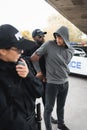 African american policeman handcuffing hooded offender