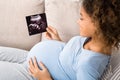 African-american pregnant woman holding ultrasound scan at home Royalty Free Stock Photo