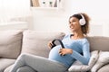 African-american pregnant woman listening to music in lving room Royalty Free Stock Photo