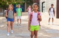 African american preteen girl with backpack walking along city street