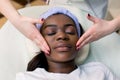 African-american pretty woman enjoying face massage at beauty salon, top view, copy space Royalty Free Stock Photo