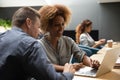 African woman mentor training caucasian intern helping colleague with software Royalty Free Stock Photo