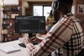 African american programmer with wireless headphones listening to music while writing code