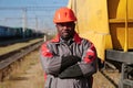 African american railway man in uniform and hard hat stands on railroad tracks