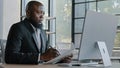 African american right-handed senior businessman look at screen holds pen notices new information on tablet paper list