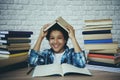 African American schoolboy holds book over head