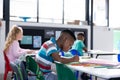 African american schoolboy working at his desk in diverse elementary class, copy space