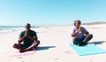 African american senior couple with cross legged sitting and meditating on beach against clear sky Royalty Free Stock Photo