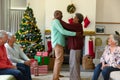 African american senior couple dancing in front of diverse male and female friends at christmas time Royalty Free Stock Photo