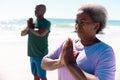 African american senior couple meditating at beach against clear sky during summer Royalty Free Stock Photo