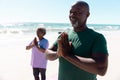 African american senior couple practicing mountain pose at beach against clear sky in summer Royalty Free Stock Photo