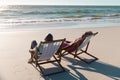 African american senior couple talking while sitting on deckchairs in front of seascape at beach Royalty Free Stock Photo