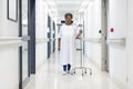 African american senior female patient with drip walking in hospital corridor Royalty Free Stock Photo