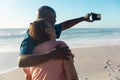 African american senior man with arm around woman taking selfie through smartphone at beach Royalty Free Stock Photo