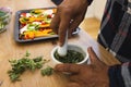 African american senior man preparing healthy meal with vegetables and seasonings in kitchen Royalty Free Stock Photo