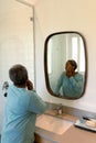African american senior woman looking at mirror in bathroom Royalty Free Stock Photo