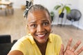 African American senior woman showing peace sign at home during a video call, wearing a yellow shirt Royalty Free Stock Photo
