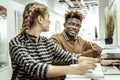 African American short-haired man pleasantly looking on female workmate