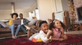 African American sibling lying on floor and watching television while parents using laptop on sofa Royalty Free Stock Photo