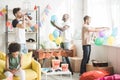 african american sitting on sofa with party garlands and young men with party horns