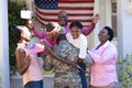 African american soldier father greeting his smiling three generation family in front of the house