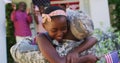 African american soldier father hugging smiling daughter with family and american flag behind