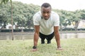 African American sportsman pushups on green grass