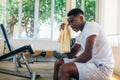 African American sportsman sitting on bench and wiping sweat with towel. Black athlete resting during fitness workout in