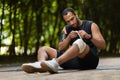African american sportsman wrapping injured knee with elastic bandage