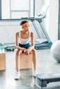 african american sportswoman in headband and headbands resting on wooden box