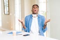 African american student man studying using notebooks and wearing headphones crazy and mad shouting and yelling with aggressive