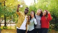 African American student is taking selfie with beautiful girls Asian and Caucasian standing in park, using smartphone Royalty Free Stock Photo