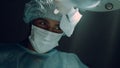 African american surgeon performing hard operation in dark clinic ward portrait.