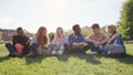 African-American teacher read book to diverse teenage students sitting on grass outside campus Royalty Free Stock Photo