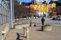 An African American teenager in a black and red sweat suit walking along the sidewalk with cars driving, a colorful mural