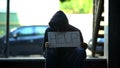 African-american teenager holding help cardboard sign, asking for alms in street