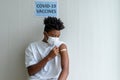 African American teenager looking adhesive bandages on his arm after received COVID-19 antiviral vaccine