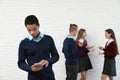 African-American teenager preferring mobile phone to classmates. Concept of internet addiction and loneliness