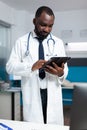 African american therapist doctor analyzing medicine prescription using tablet