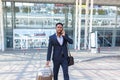 African american tourist businessman walks public transport building with luggage background, rear back view Man in formal suit Royalty Free Stock Photo