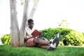 African american university student relaxing on campus.Young black man reading book outdoors. Royalty Free Stock Photo