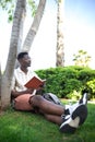 African american university student relaxing on campus.Young black man reading book outdoors. Copy space. Royalty Free Stock Photo