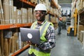 African american Warehouseman checking delivery, stock in warehouse on laptop. Warehouse manager using warehouse