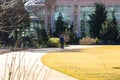 An African American wearing black man walking along a curved smooth footpath in the garden surrounded by yellow winter grass