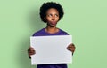 African american woman with afro hair holding blank empty banner smiling looking to the side and staring away thinking Royalty Free Stock Photo