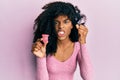 African american woman with afro hair holding menstrual cup annoyed and frustrated shouting with anger, yelling crazy with anger